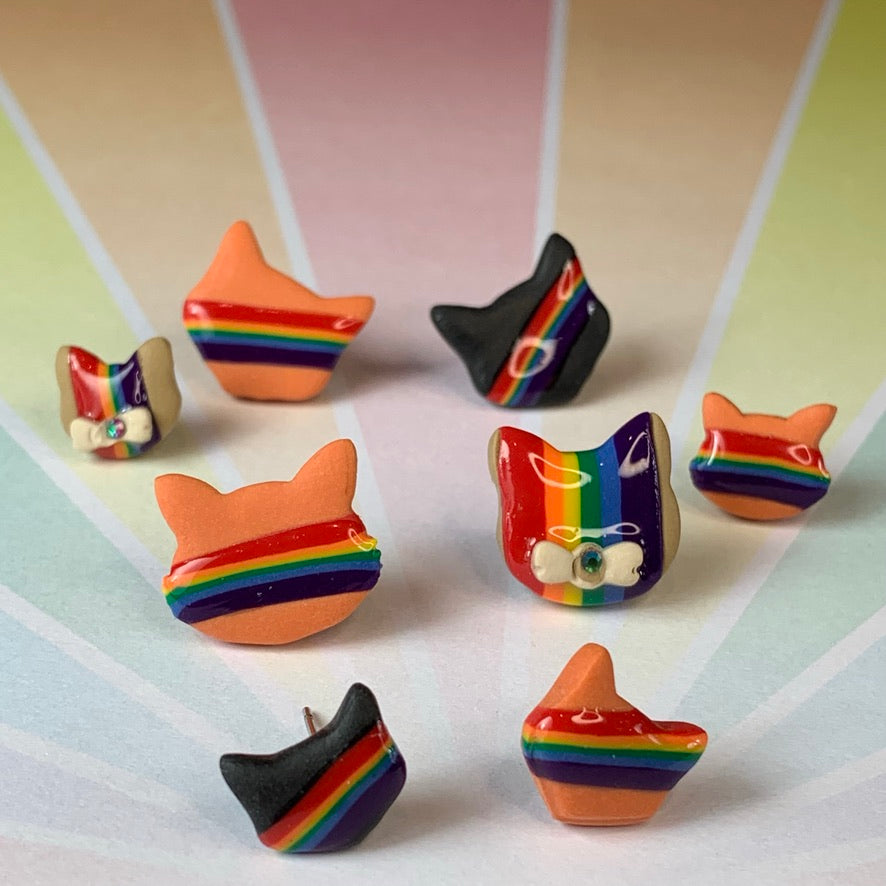 Our vibrant Rainbow Cat Stud Earrings, available in Black Cat, Orange Cat and Brown Cat variations in two sizes. These earrings perfectly blend feline charm with a brilliant rainbow symbol. The rainbow adorns the front of each cat, symbolizing unity and pride. Our Rainbow Cat Stud Earrings are a heartfelt expression of love for cats, appreciation for rainbows, and celebration of LGBTQIA pride.