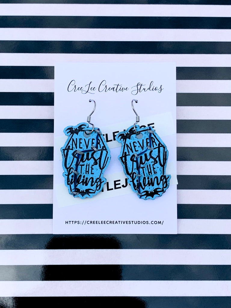 A pair of light blue earrings with black text and detailing, displayed on a black and white striped card with the brand name 'CreeLee Creative Studios'.
