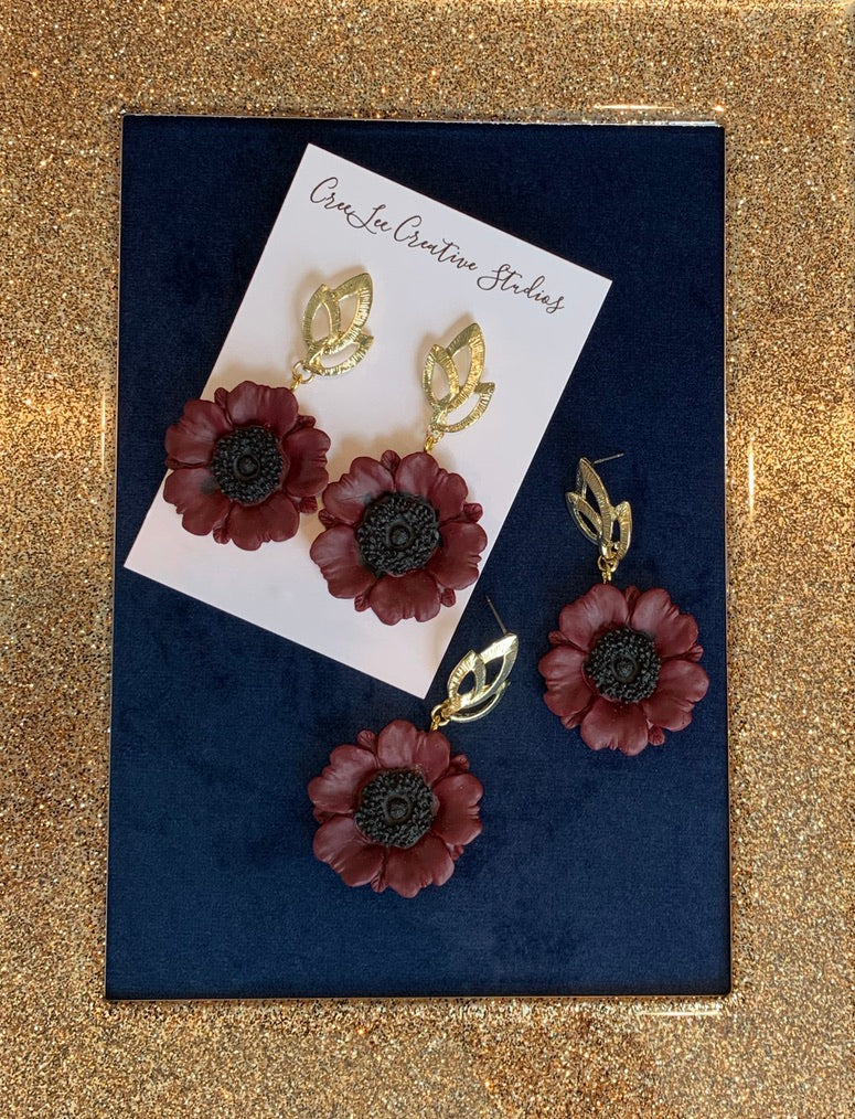 Maroon Poppy Earrings on a blue background inside a gold frame.