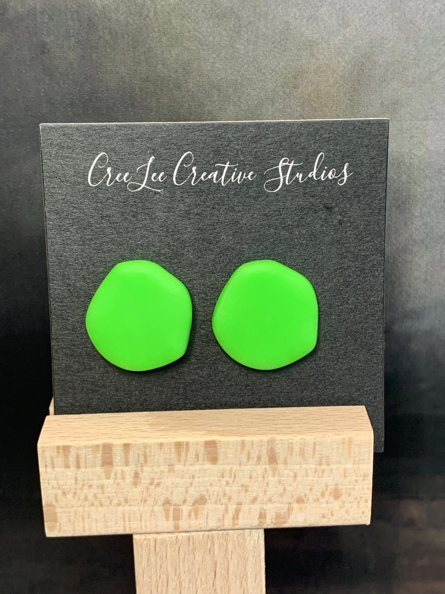 A pair of abstract circle studs in neon green.