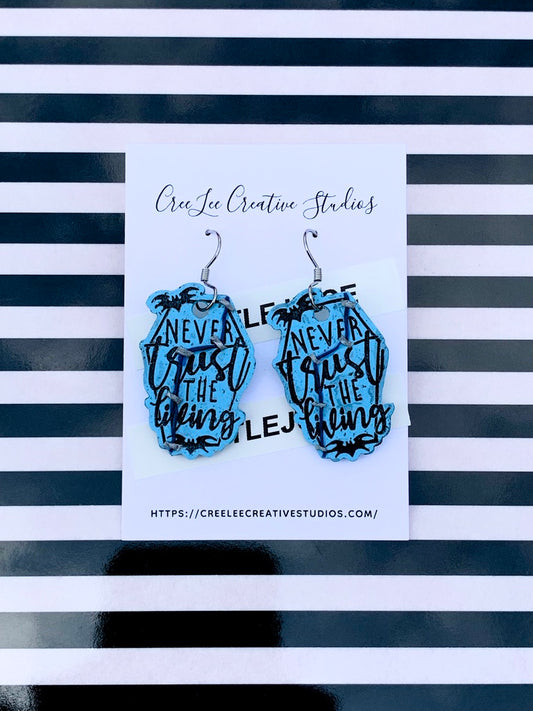 A pair of light blue earrings with black text and detailing, displayed on a black and white striped card with the brand name 'CreeLee Creative Studios'.