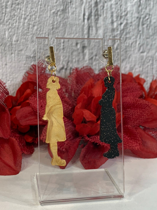 Handmade Wednesday & Enid silhouette earrings — lightweight polymer clay dangle earrings inspired by the iconic face-off at Nevermore Academy. These handcrafted silhouette earrings come in a dual-tone set: a pearlescent gold-beige Enid and a matte black, gold-flecked Wednesday. Perfect for Addams Family jewelry, Wednesday Addams earrings, Nevermore Academy accessories, and gothic cosplay earrings.