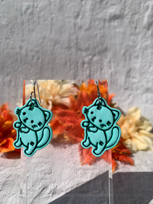 Spooky Cat Zombie Earrings — handmade polymer clay statement dangles in light green with hand-etched zombie stitching and patch details. Lightweight and durable, each cat charm features high-contrast green linework and is finished on silver-toned stainless steel fishhook findings. Ideal for searches like zombie cat earrings, spooky cat jewelry, polymer clay cat earrings, and Halloween cat accessories.