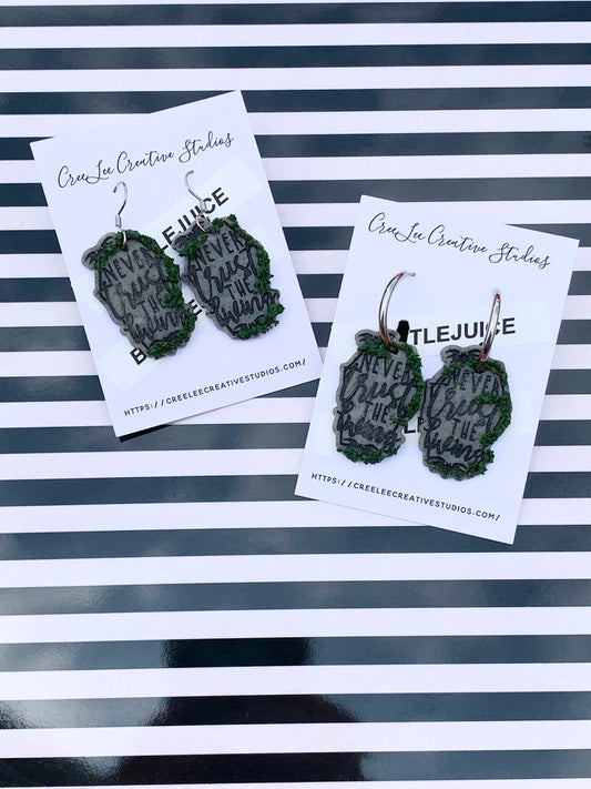 Never Trust the Living Tombstone with Growing Moss Earrings on a black and white stripped background