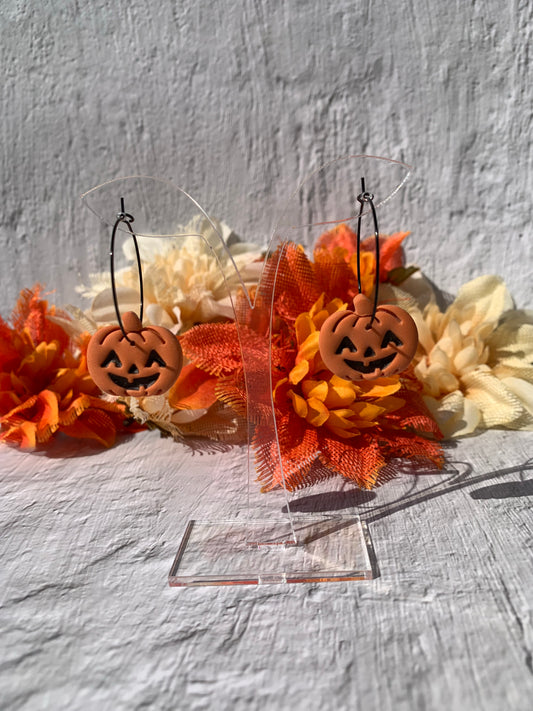 Orange jack-o-lantern earrings on black hoop